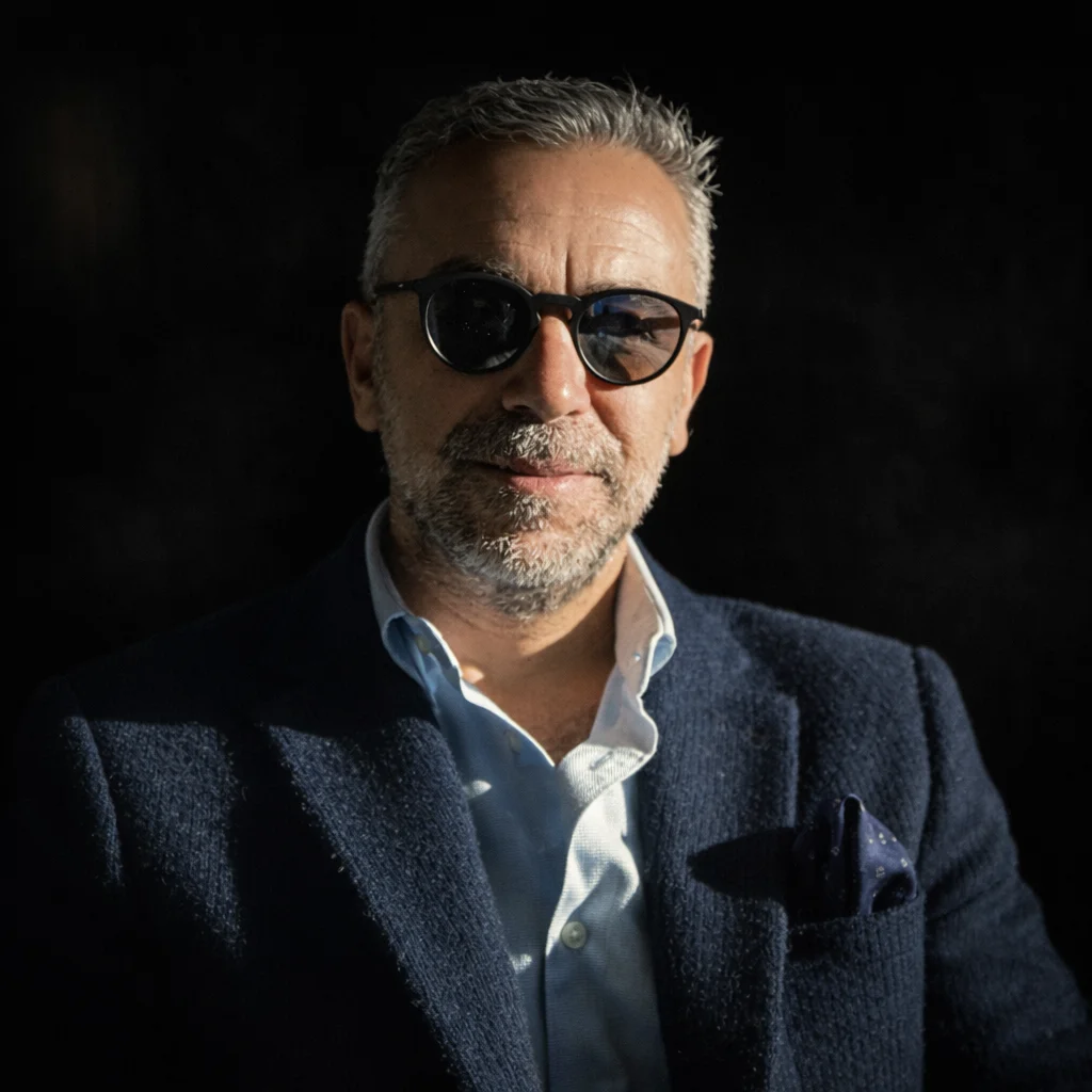 Portrait of Can Topçu in a navy tweed jacket and dark glasses