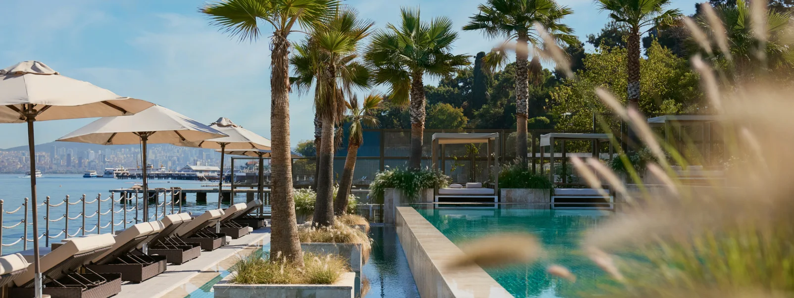 Prince's Palace pool terrace with palms, loungers and the Istanbul skyline across the water